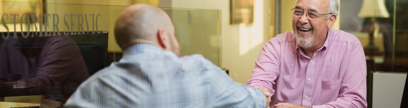Personal Banking - Two men in office shaking hands across a desk